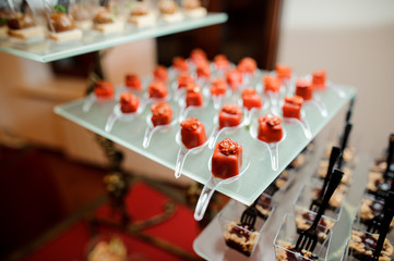 Set of salty small appetizers in a red glaze decorated with sun-dried tomato