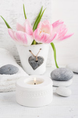 Pink tulips, pebbles and lit candle