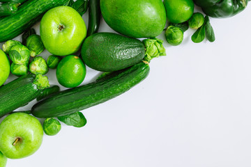 green fruits and vegetables on white background with copy space by diagonal