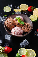 Portion of ice cream scoops with fruit on black
