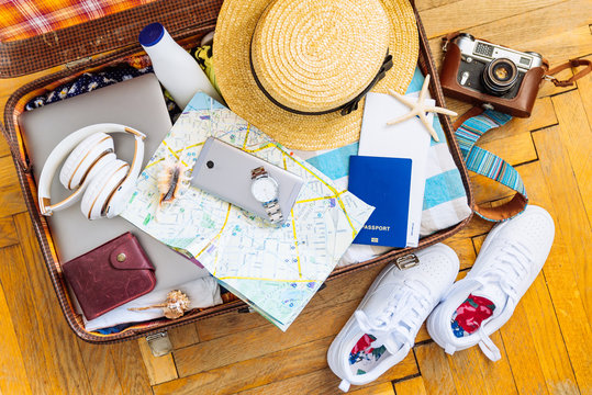 woman staff in suitcase. travel concept. camera laptop wallet hat on floor. overhead view