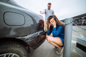 sad woman near scratched car. man shouting on woman. car acciden
