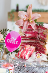 Tasty pink cake on a dessert table at a baby shower party for a girl