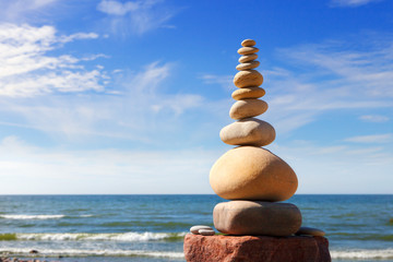 Fototapeta na wymiar White, round stones balance on a background of blue sky and sea