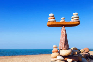 Symbolic scales of stones on a background of blue sky and sea.