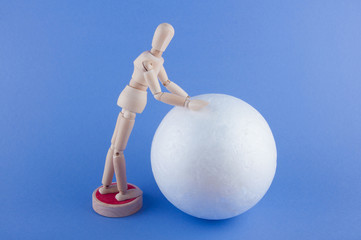 Wooden man rolling big ball on blue background