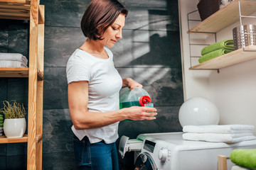 Woman pouring liquid laundry detergent In the bottle cap