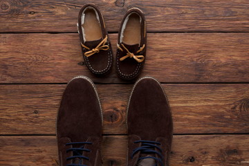 Fototapeta na wymiar Male and child shoes on rustic wood background