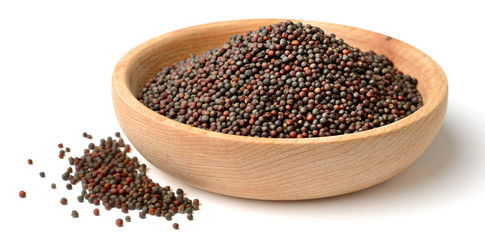 dried canola seeds in the wooden plate, isolated on white