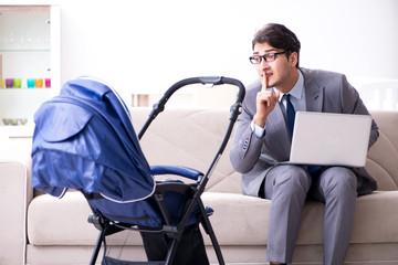 Businessman looking after newborn baby at home and teleworking