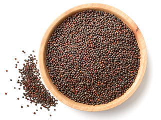 dried canola seeds in the wooden plate, isolated on white, top view