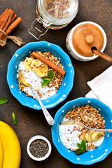 Morning breakfast for two. Yogurt with fruit, granola with cinnamon and chia seed in a plate on a concrete background.