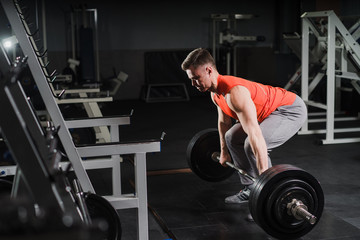 Strong handsome fit man exercising in the gym. Personal trainer workout. Athletic man working out his muscles at deadlift. Fitness, healhty lifestyle, bodybuilding concept.
