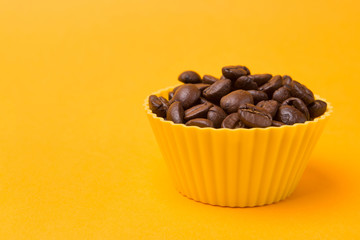 coffee beans in a yellow container on a yellow background, concept