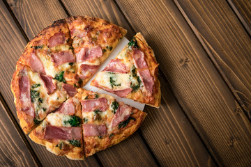 Homemade pizza with spinach, smoked ham. wooden background, copy space.