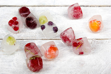 Obraz na płótnie Canvas Berries frozen in ice cubes with mint on wooden table background.