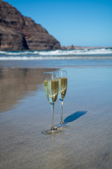 Two glasses of champagne or cava sparkling wine served on the white sandy tropical beach, luxury resort with sea view, romantic vacation