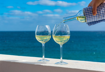 Waiter pouring glass of white wine on outdoor terrace with sea view