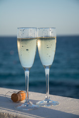 Two glasses with champagne or cava served outside on terrace, luxury resort with sea view, romantic vacation