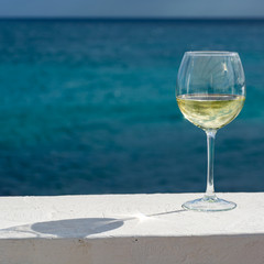 One glass of cold white wine served on outdoor terrace with sea view, party background