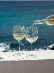 Waiter pouring glass of white wine on outdoor terrace with sea view