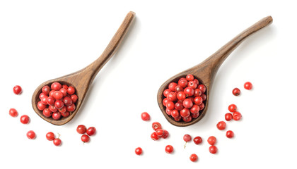 dried pink peppercorns in the wooden spoon, isolated on white, top view