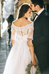 Handsome groom kissing happy bride in street