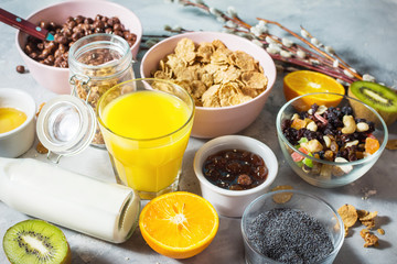 Fototapeta na wymiar Healthy breakfast with bowl of cereal, orange juice, granola, milk, jam and fruits on concrete background.