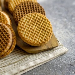 A cookie of round shape lies on a wooden kitchen board and on a napkin. On a gray abstract background. Copy space.