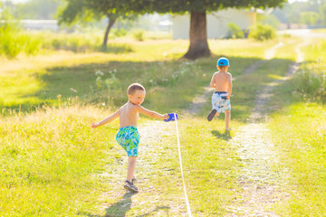 guys running on a dirt road. The boy in the shorts holds the leash and looks back