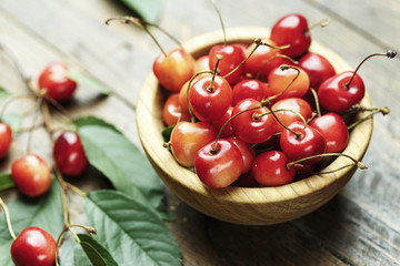 Ripe cherries with leaves on a wooden background