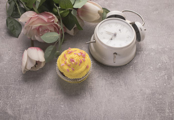 Muffin whith flowers and clock on grey background on top view