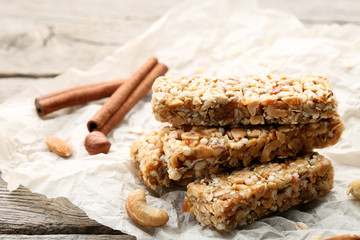 Tasty granola bars with different nuts and cinnamon on wooden table