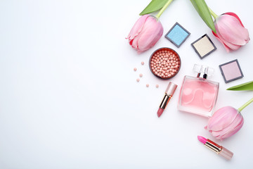Makeup cosmetics with perfume bottle and tulip flowers on white background