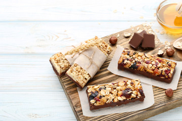 Tasty granola bars with nuts and chocolate pieces on wooden table