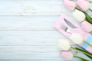 Fototapeta na wymiar Kitchen cutlery with napkin and tulip flowers on wooden table