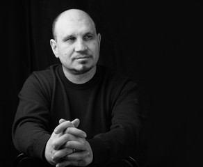 Black and white photo. Portrait of a young man with folded hands.