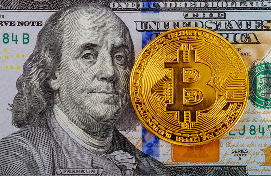 Golden Bitcoins on US dollars. Digital currency close-up. New virtual money. Crypto currency top view. Real coins of bitcoin on banknotes of one hundred dollars.