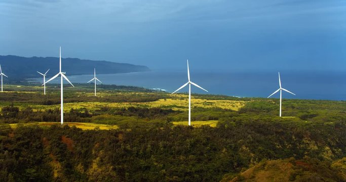Aerial view of windmills spinning on sunny summer day in tropical forest environment 