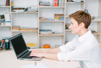 girl working behind laptop bright office shelves shelves