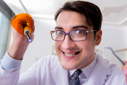 Funny dentist with curing light in medical concept