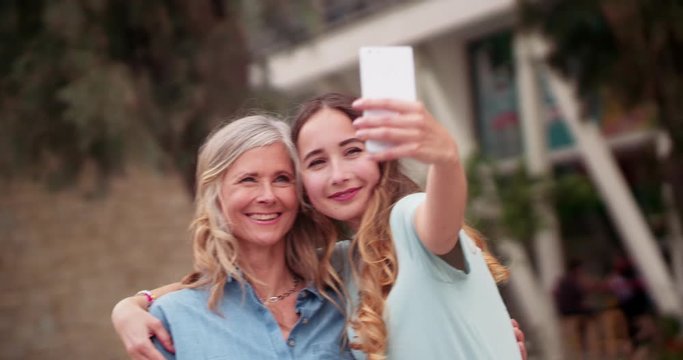 Beautiful senior mother and daughter taking selfies in the city
