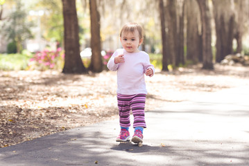 Little girl walking on a sidewalk at a park