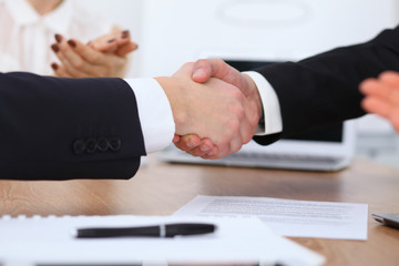 Close up of business people shaking hands at meeting or negotiation in the office. Partners are satisfied because signing contract