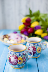Easter sweets for the holiday. Spring. Bright colors on coffee mugs. A bouquet of fresh tulips