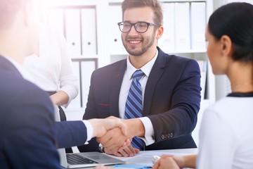 Business handshake at meeting or negotiation in the office. Partners are satisfied because signing contract or financial papers