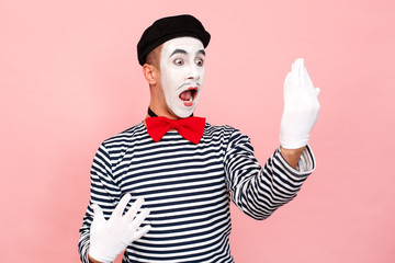Street artist in a striped sweater, white gloves looking mirror, scream