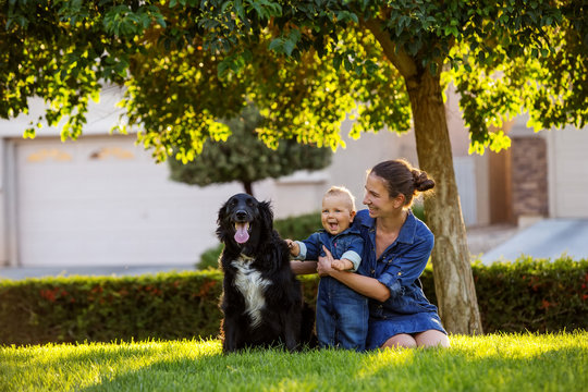 A Mother With Baby Son And Black Dog In Green Neighborhood