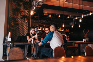 Group of mixed race young men talking in lounge bar. Multiracial friends having fun in cafe
