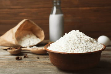 Bowl with flour on wooden table